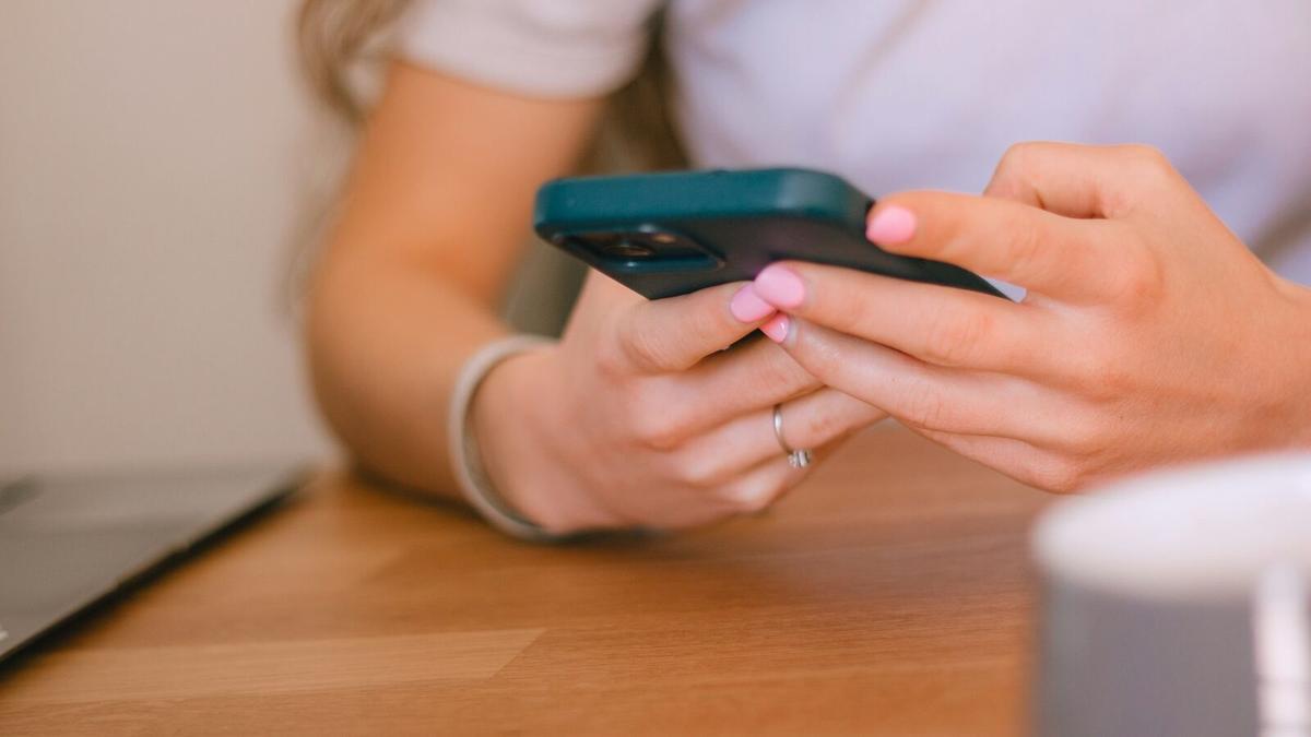 Someone reading their phone at a wooden table