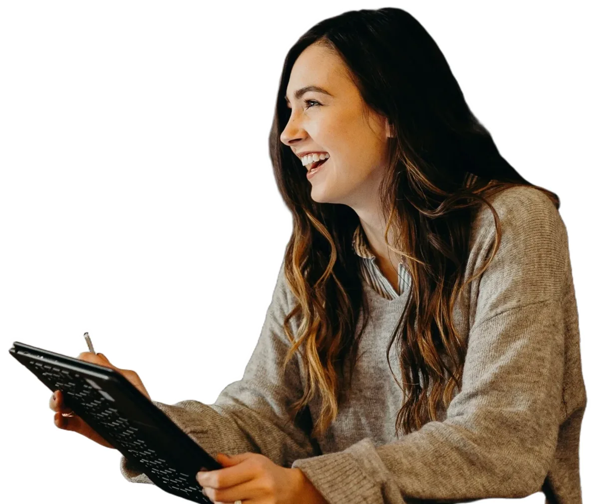 Someone with long dark hair in a grey sweater laughing, holding a tablet and stylus